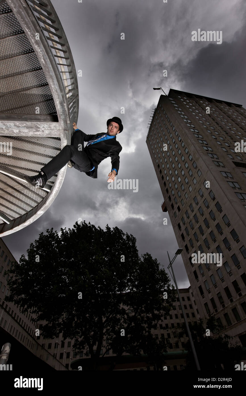 Parkour runner in suit hanging from corporate building Stock Photo