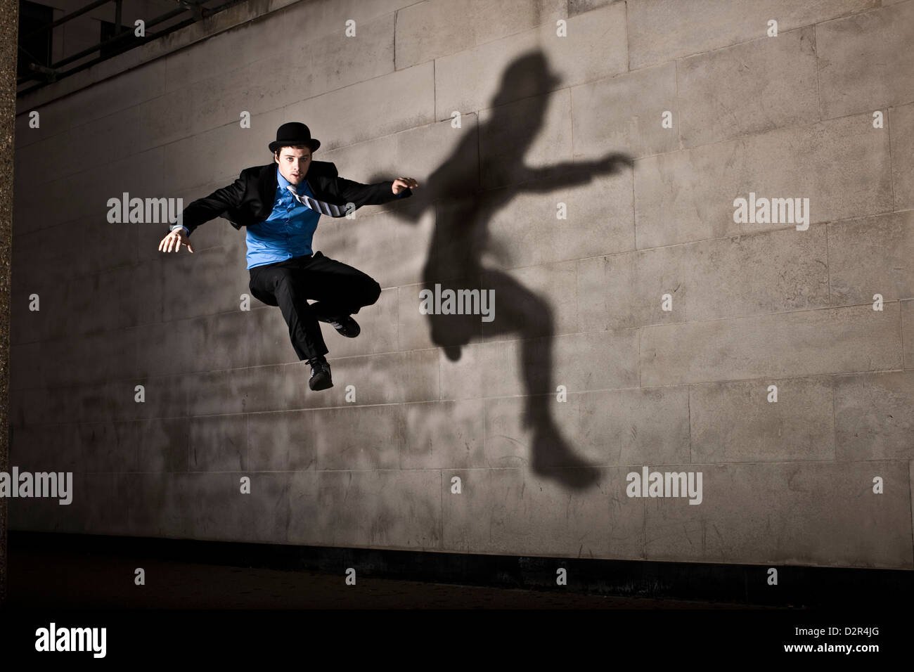Parkour runner in bowler hat with shadow, jumping Stock Photo