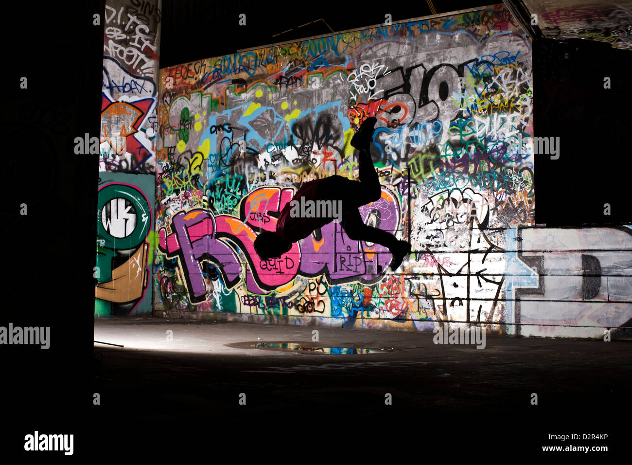 Parkour runner in mid air jump with graffiti Stock Photo