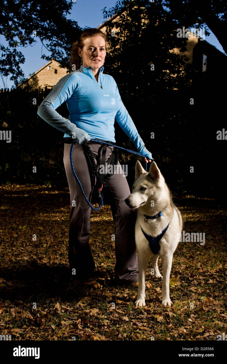 Portrait of female jogger with husky dog, animal training Stock Photo