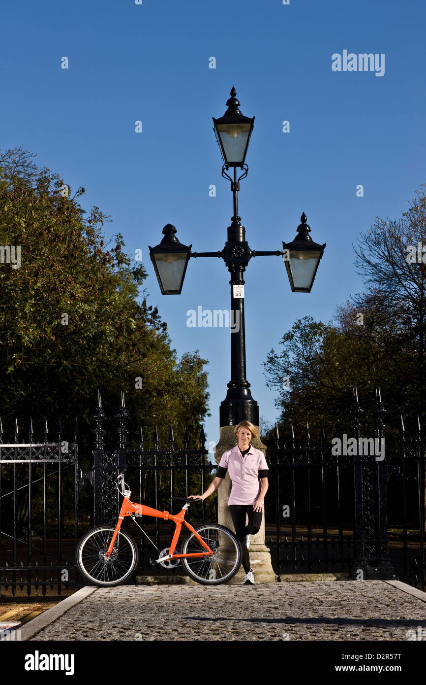 Female cyclist stands with bike at park railings, London Stock Photo