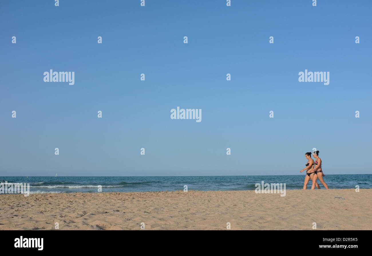 Two women walk along Oliva town beach in Spain Stock Photo
