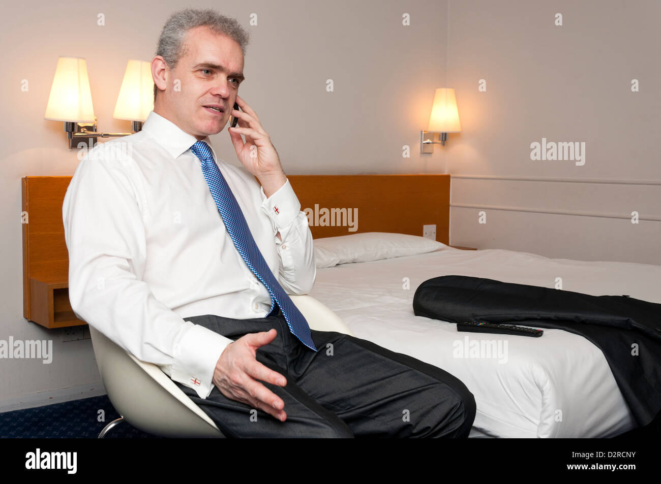 Business man in hotel room using mobile phone. Stock Photo