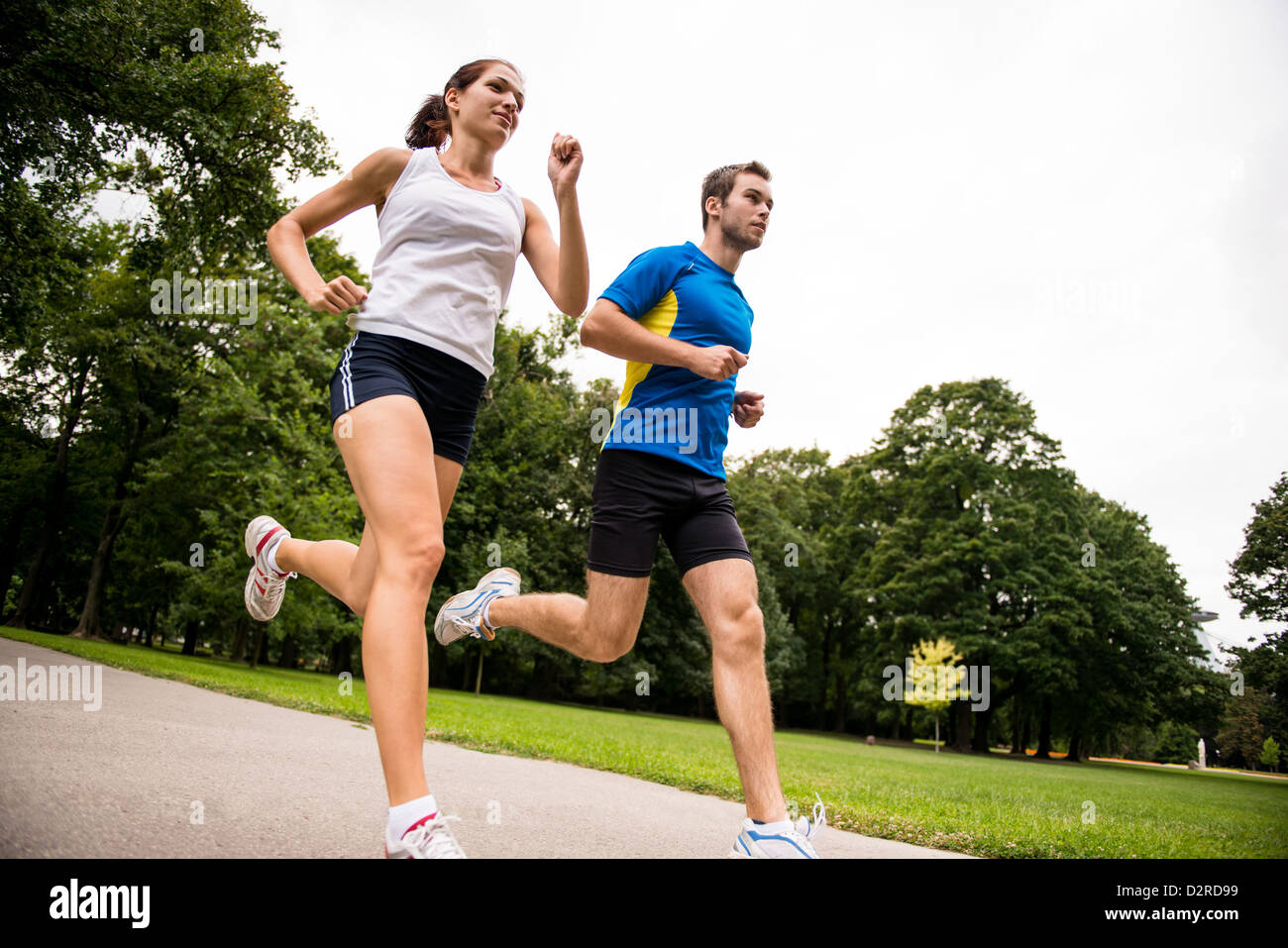 Low angle photo of young couple jogging outdoor in park Stock Photo