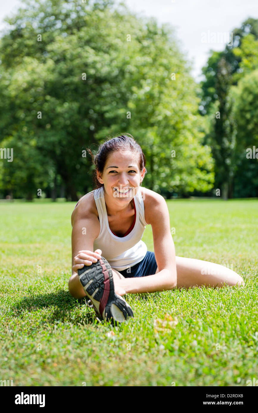 Young fitness woman stretching muscles before sport activity - outdoor in park Stock Photo