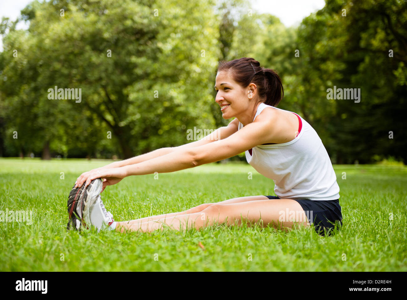 Young fitness woman stretching muscles before sport activity - outdoor in park Stock Photo