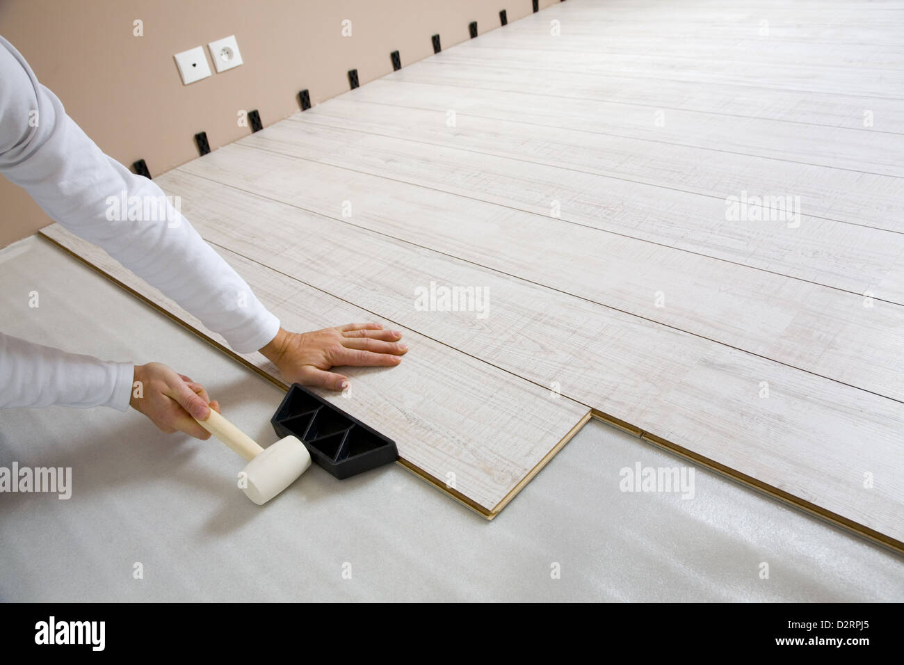 Worker laying a floor with laminated flooring boards Stock Photo