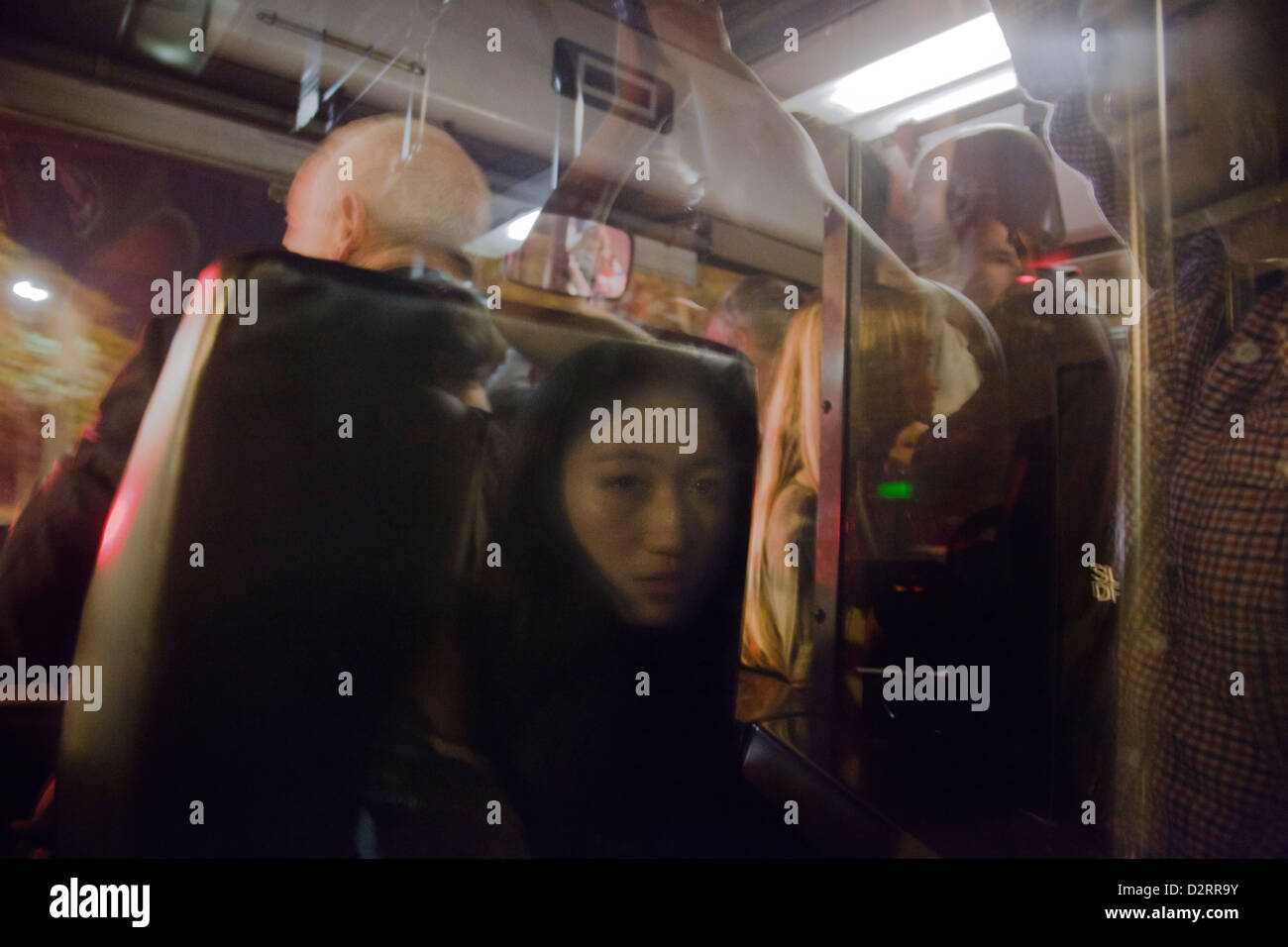 Asian woman mirrored in the window behind the driver of an overcrowded bus in Paris Stock Photo