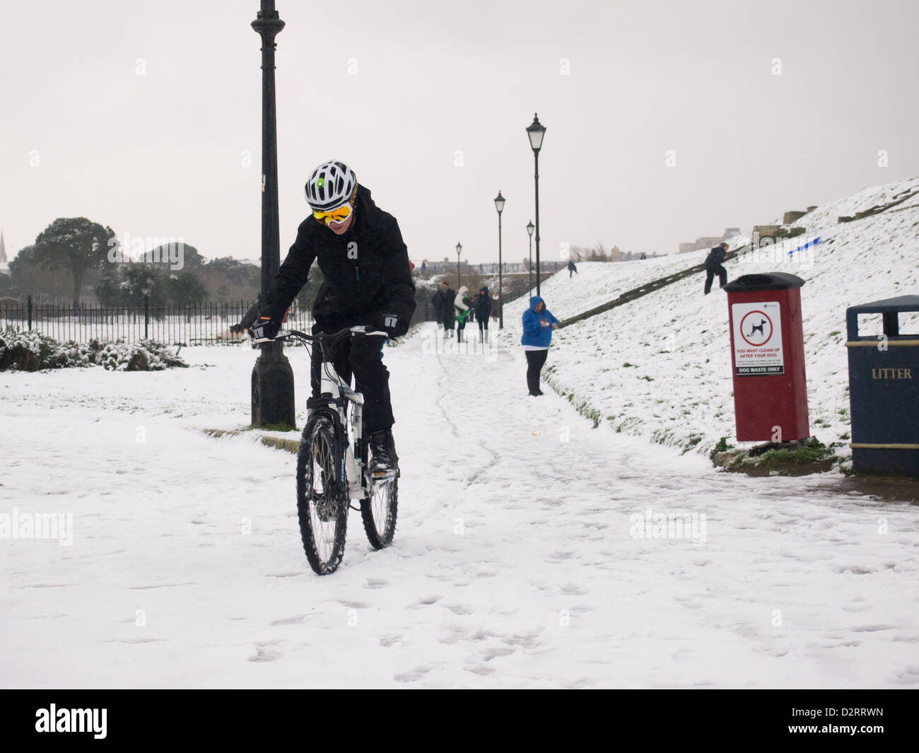 Man Riding a bike in the snow wearing cold weather clothing Stock Photo