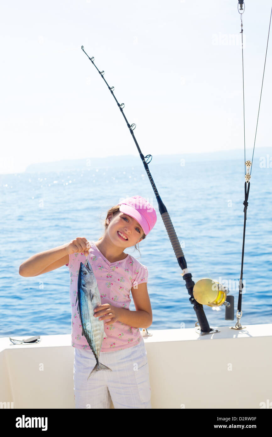 child little girl fishing in boat holding little tunny tuna fish