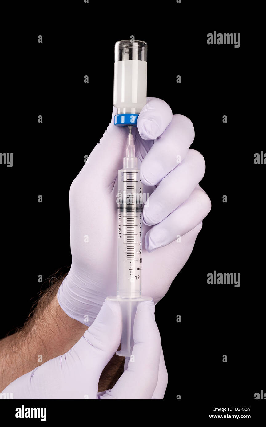 A doctor draws narcotics from a vial in preparation to inject a patient. Stock Photo