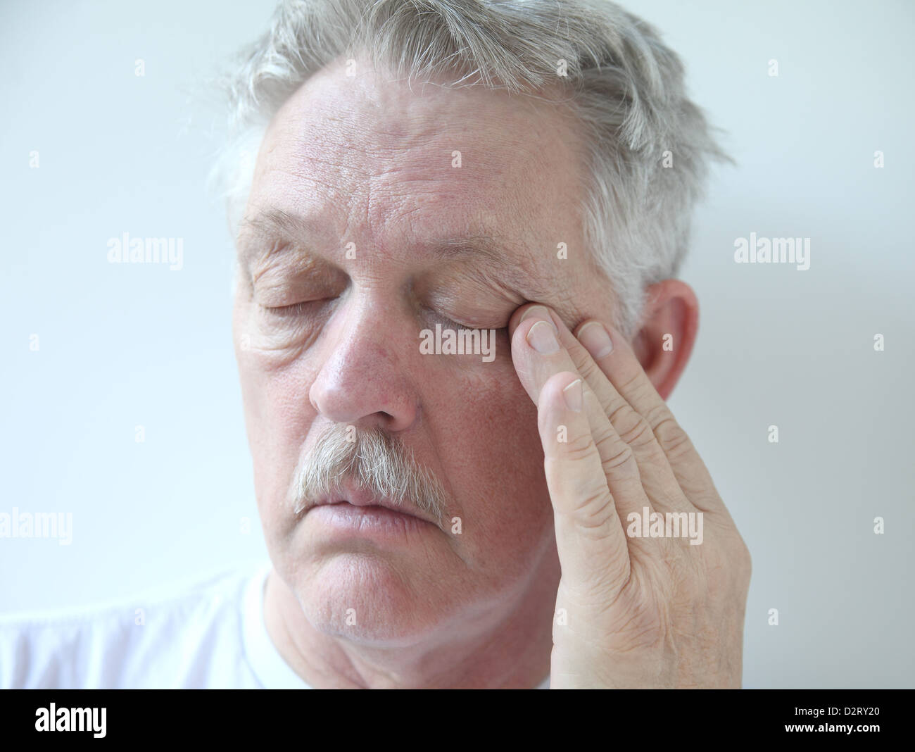 senior rubs the corner of his eye Stock Photo