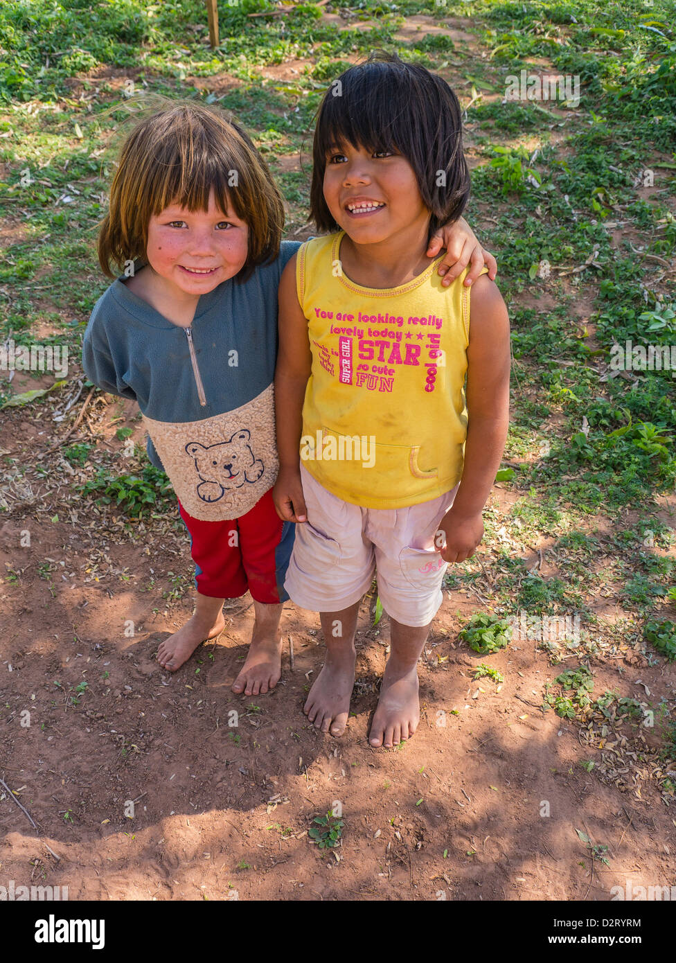 Two young Paraguayan Hispanic girls who are best friends stand, smiling, with one having her arm around the other. Both girls ar Stock Photo