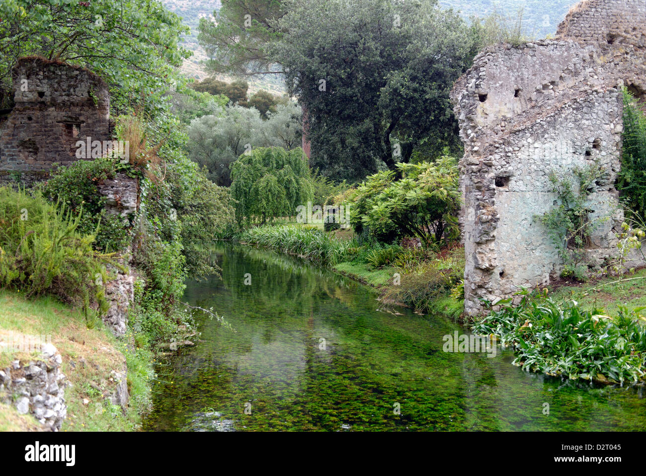 View along the romantic river and the ruins of the medieval village. Garden of Ninfa. Lazio. Italy. Stock Photo