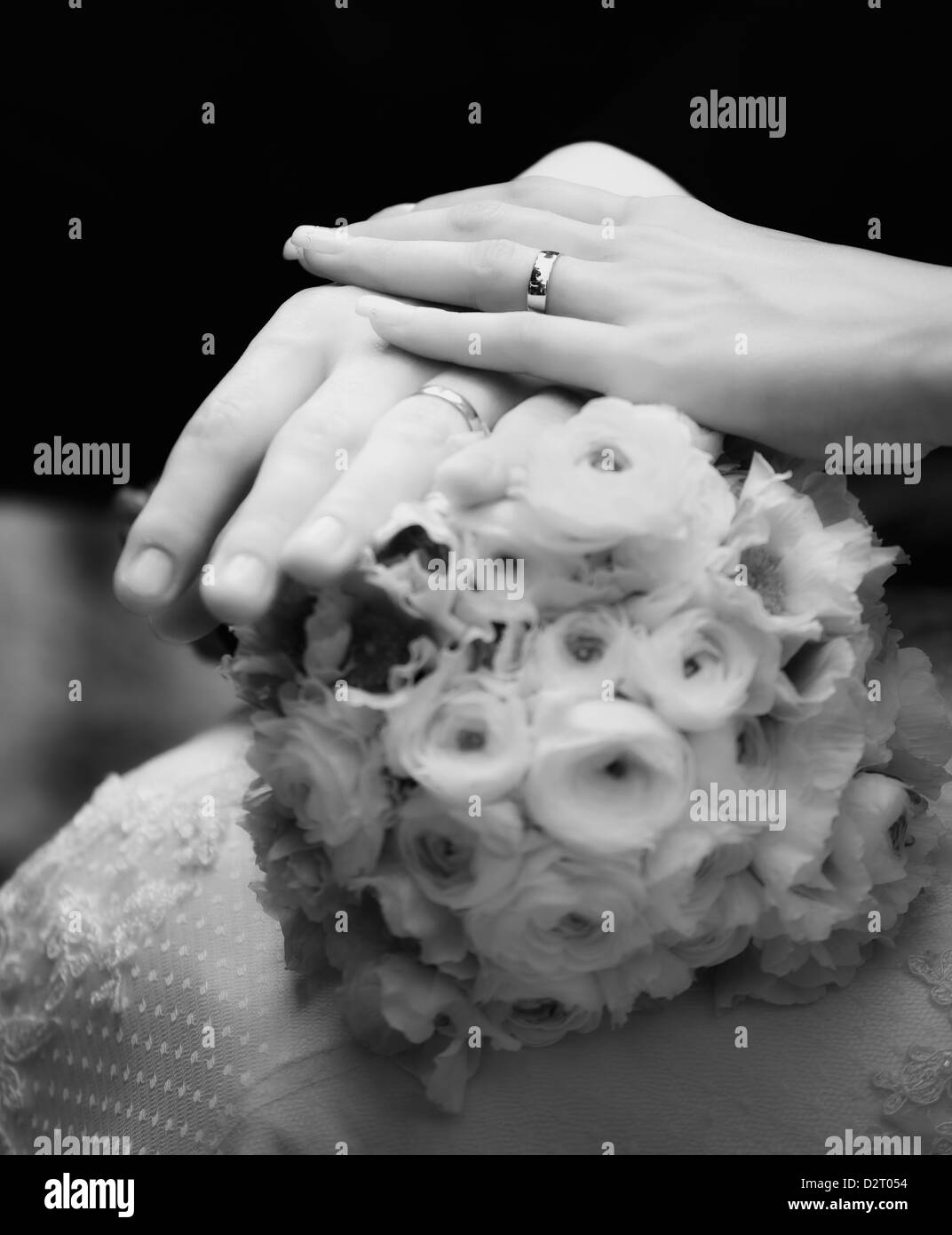 Closeup of hands of newly weds and flower bouquet in black and white, soft focus. Stock Photo