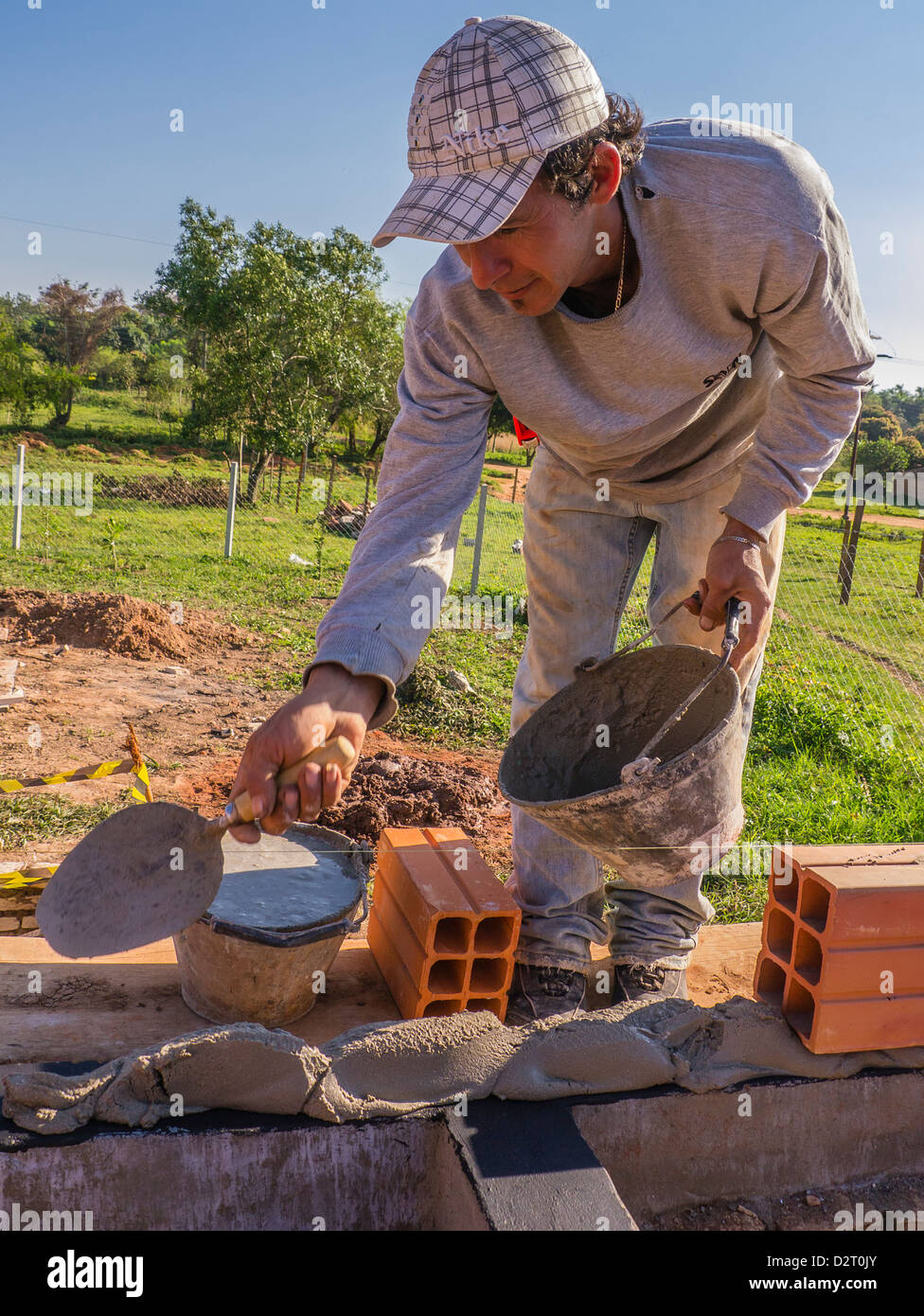 The lead mason works on the house construction assisted by international volunteers on a Habitat for Humanity site in Luque, Par Stock Photo