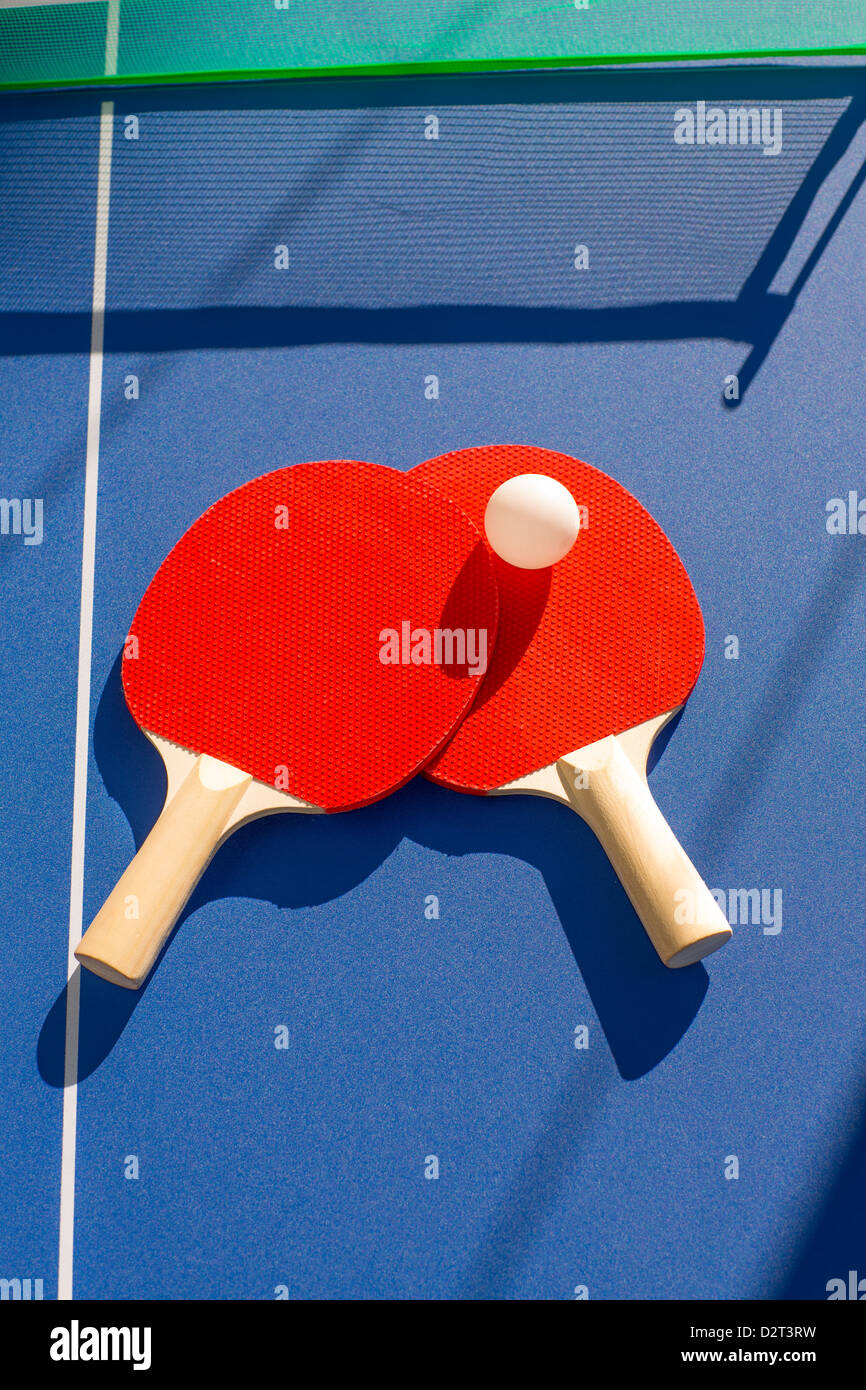 table tennis ping pong two paddles and white ball on blue board Stock Photo