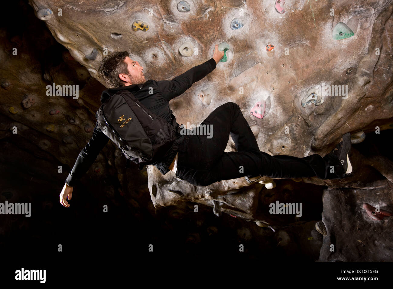Man hanging from climbing wall, London, UK Stock Photo