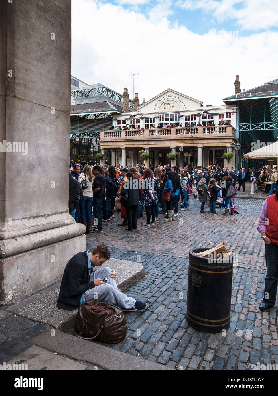man with mobile phone sitting on the ground in covent garden Stock Photo