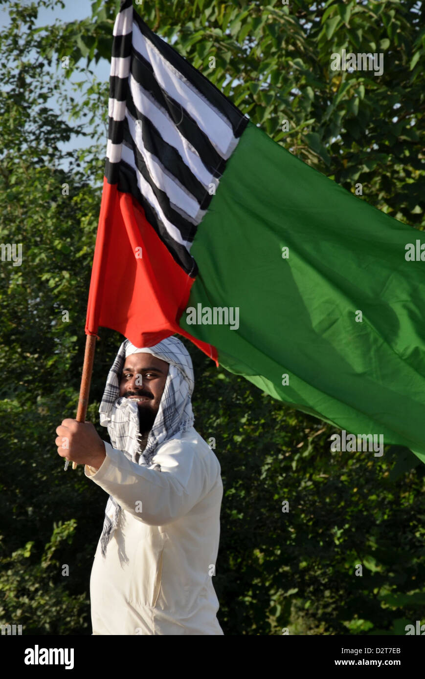 Pakistani religious political activist waves party flag heading towards a rally in defense of Islam's Prophet. Stock Photo