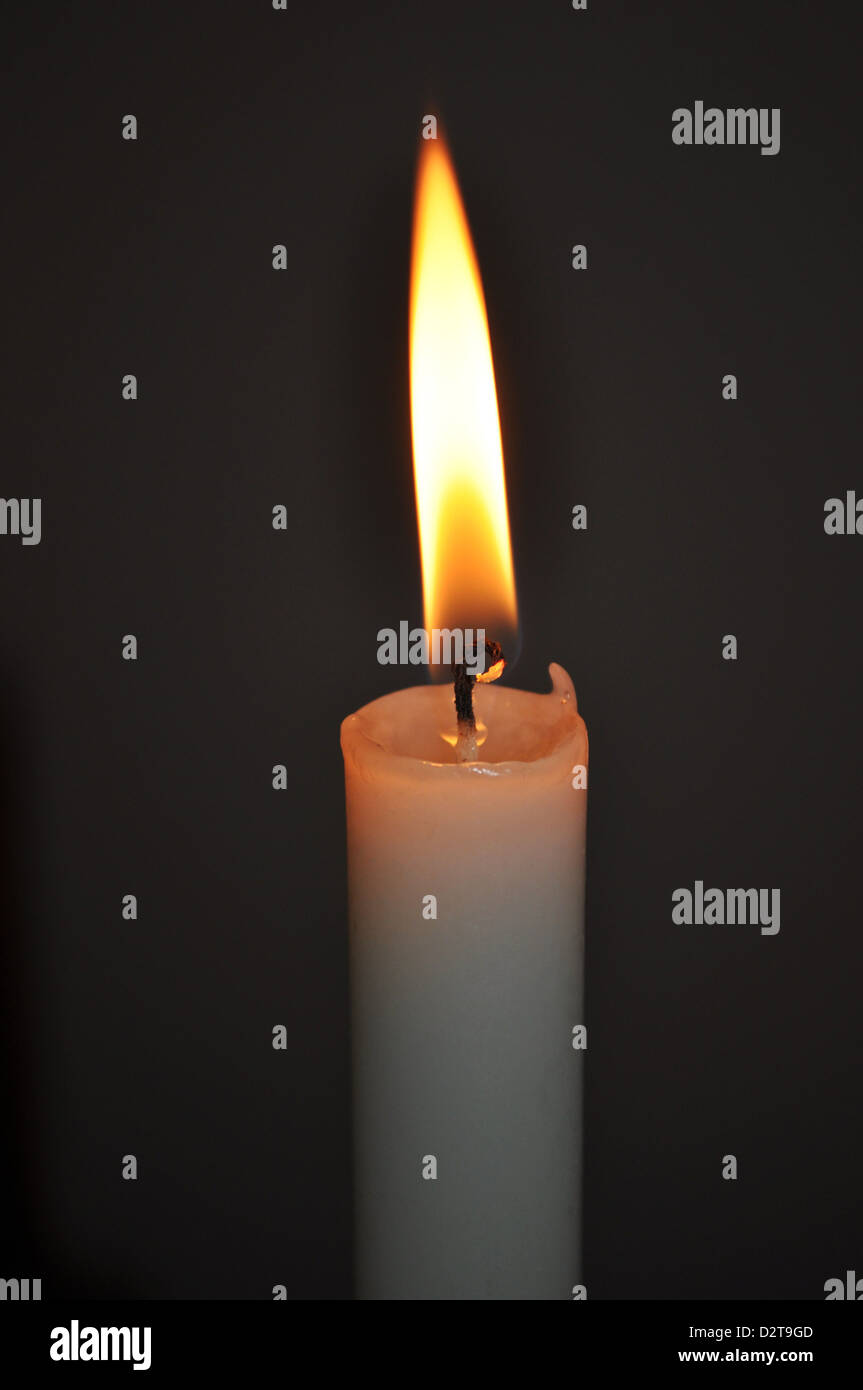 Single White Candle Burning it's Flame in a Dark Room Stock Photo - Alamy