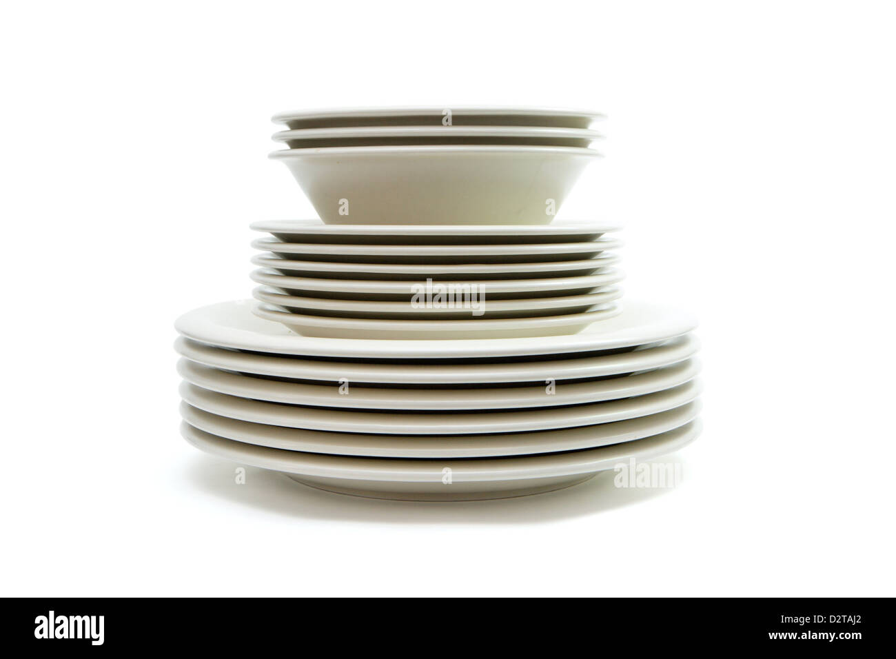 Stack of plain beige dinner plates, soup plates and saucers isolated