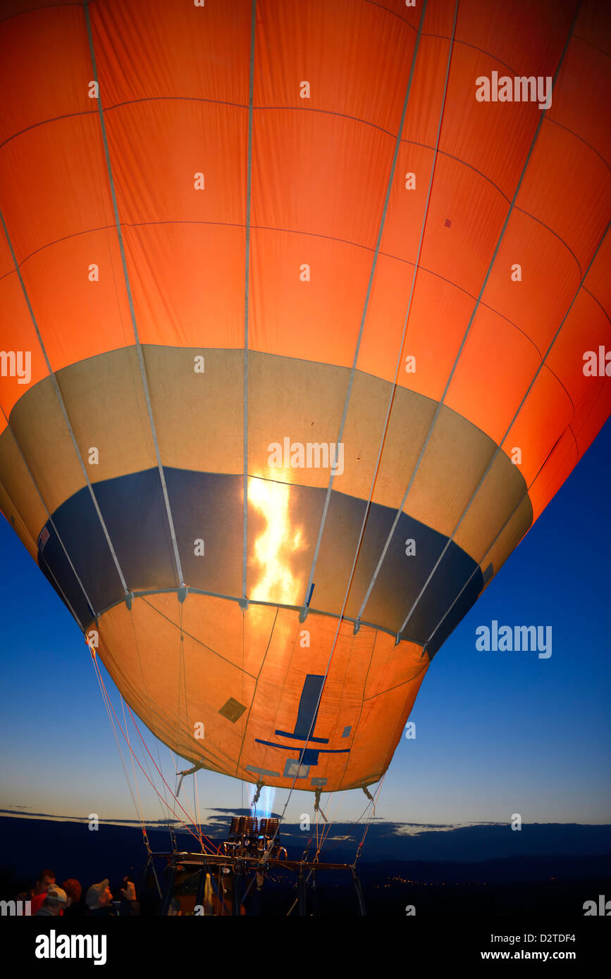 Propane heater inflating a hot air balloon at dawn with Urgup city lights Cappadocia Turkey Stock Photo