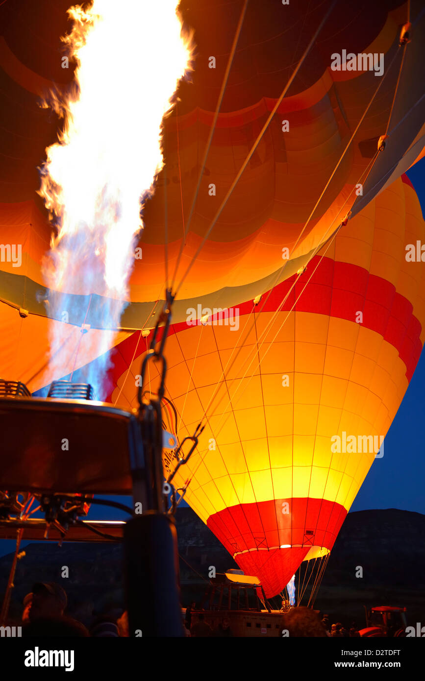 Red glow of blasts from propane heaters inflating hot air balloons at dawn Cappadocia Turkey Stock Photo