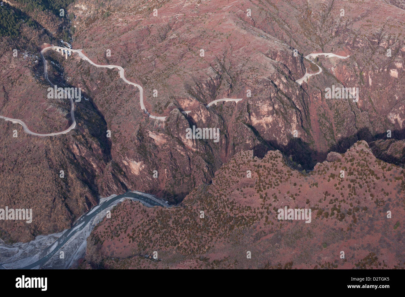 AERIAL VIEW. Winding road above the Var River in a landscape of red-brown pelite rock. Guillaumes, Daluis Gorge, French Riviera's backcountry, France. Stock Photo