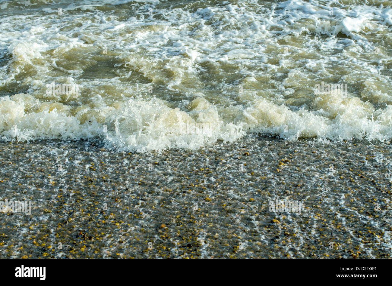 Turbulent wave dragging across a pebble shore Stock Photo