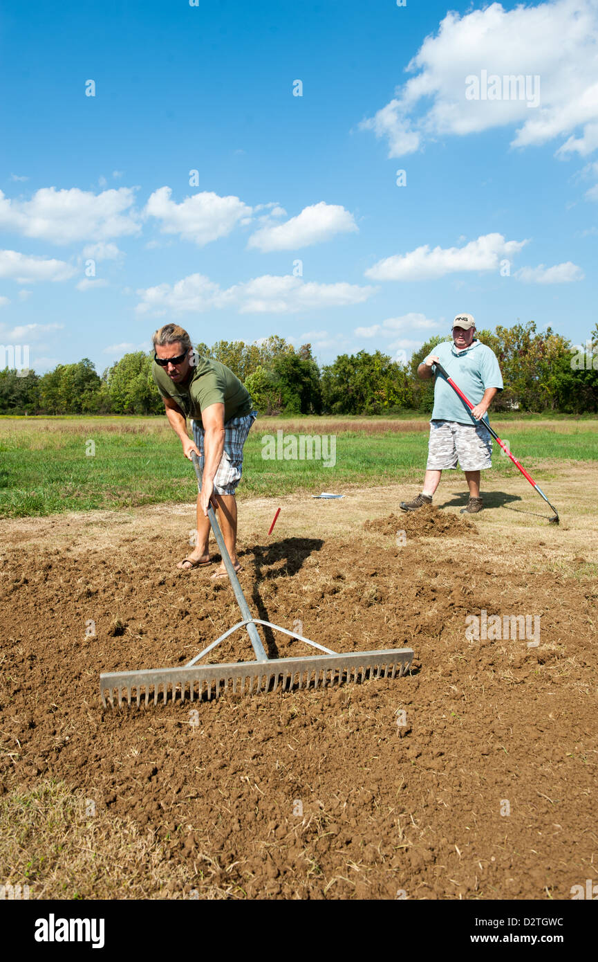Men raking soil to plant a garden Stock Photo