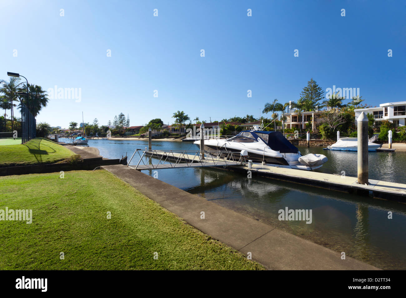 Waterfront Backyard With Tennis Court And Luxury Yacht Stock Photo