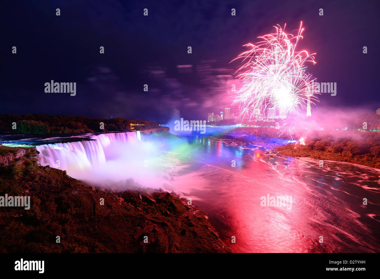 Niagara Falls lit at night by colorful lights with fireworks Stock