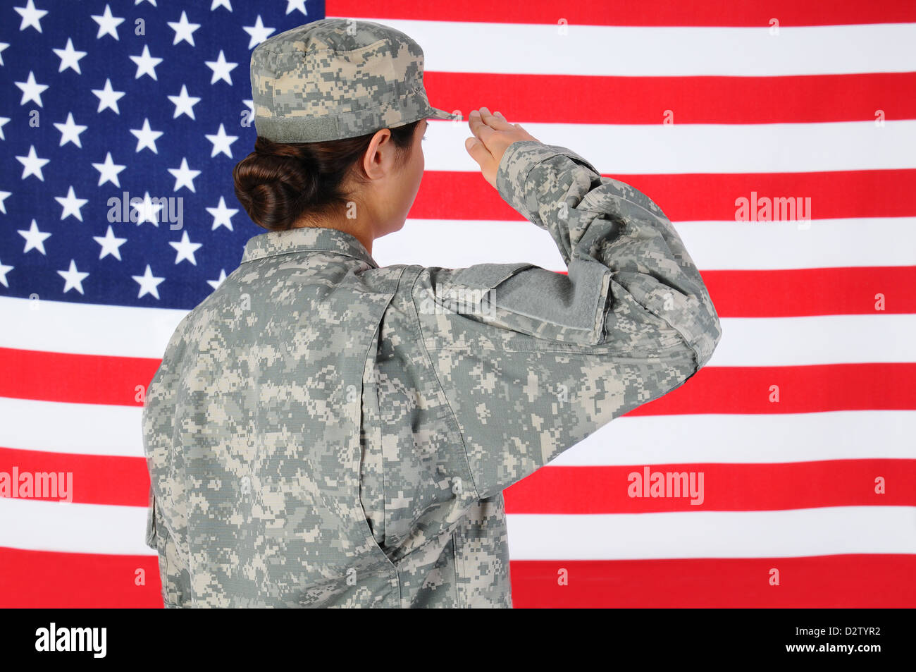 Closeup of an American Female Soldier in combat uniform saluting a flag. Stock Photo