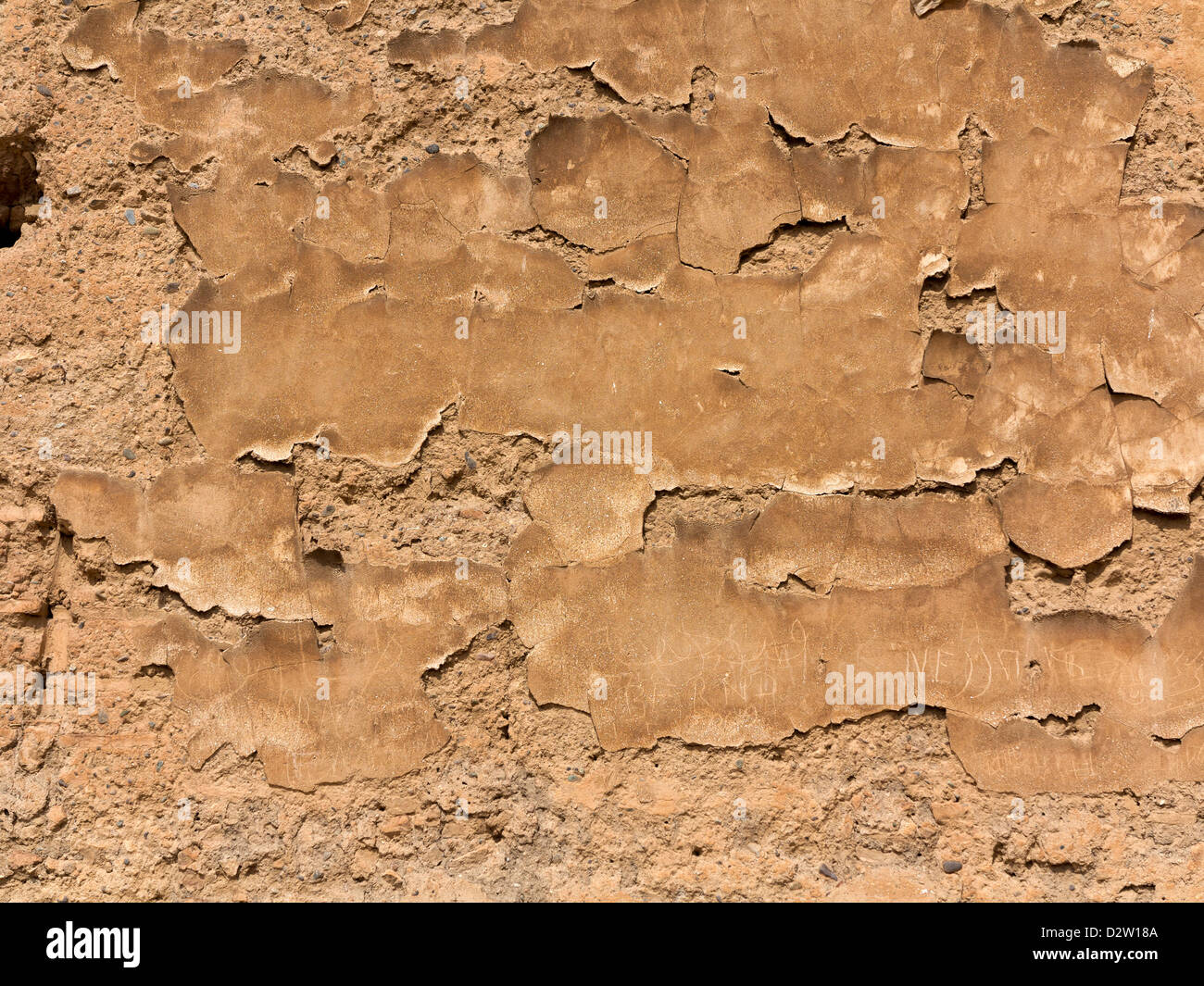 Close up detail of vertical wall surface showing flaking fine surface plaster with scratched graffit Stock Photo