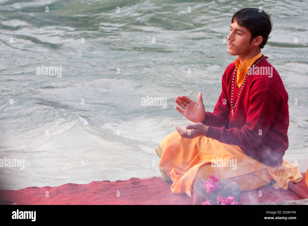 India, Rishikesh. Young Monk Praying Evening Prayer (Aarti) at the Parmarth Niketan Ashram, on the Banks of the Ganges (Ganga). Stock Photo