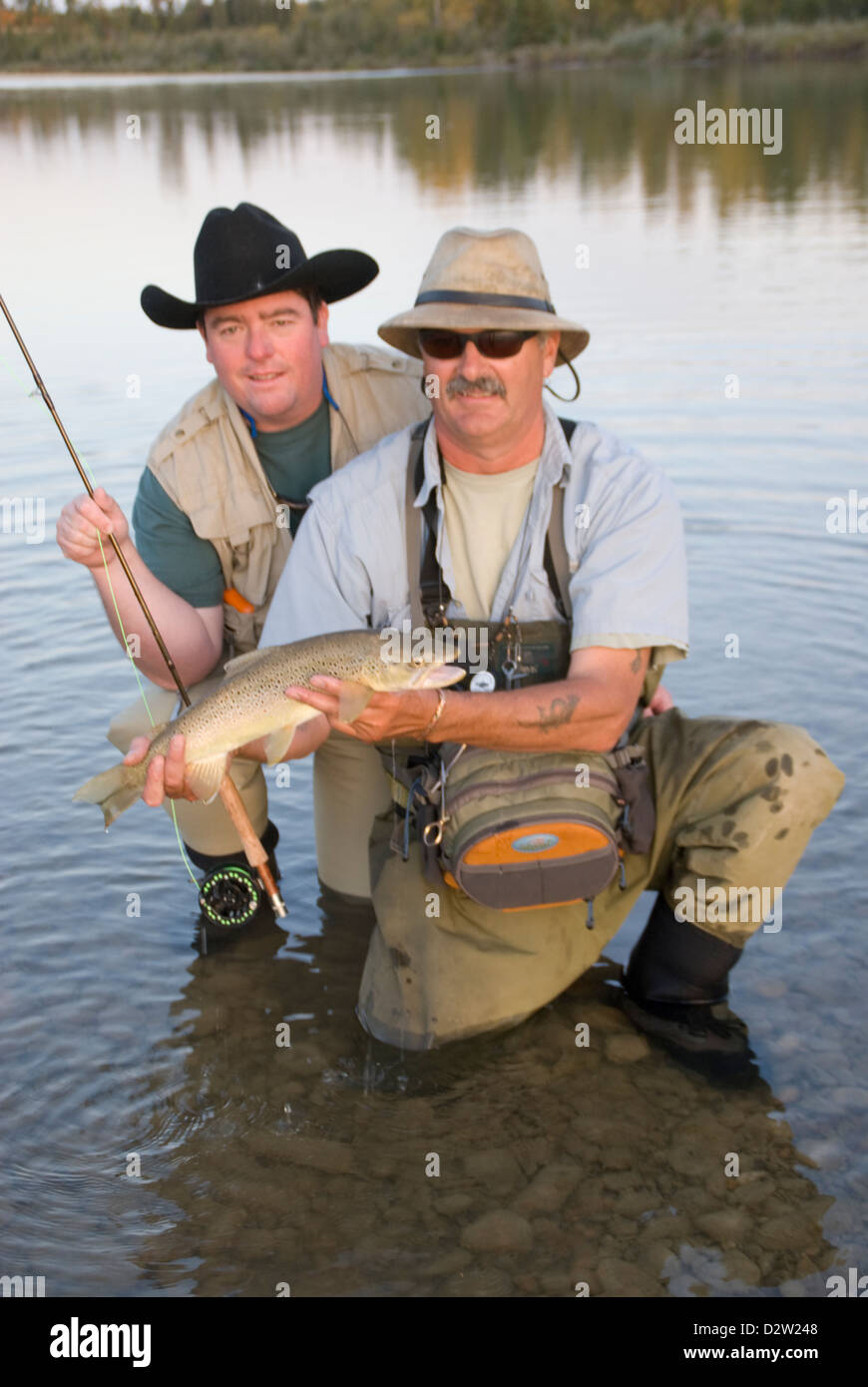 Fly fishing guide holds a trophy sized Brown trout before releasing it