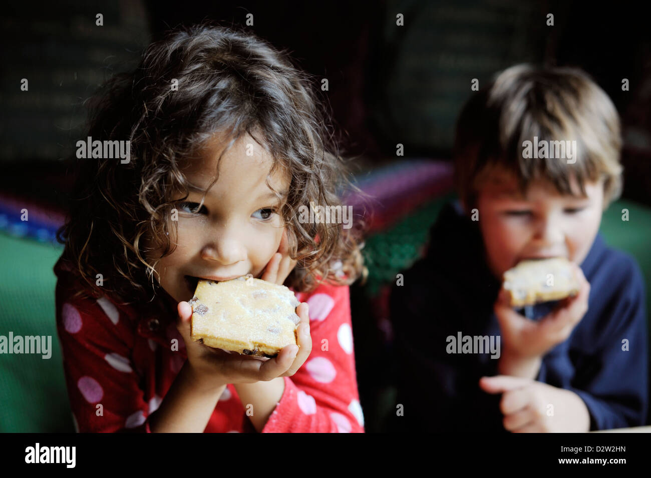 Young children eating cakes, Wales. Stock Photo