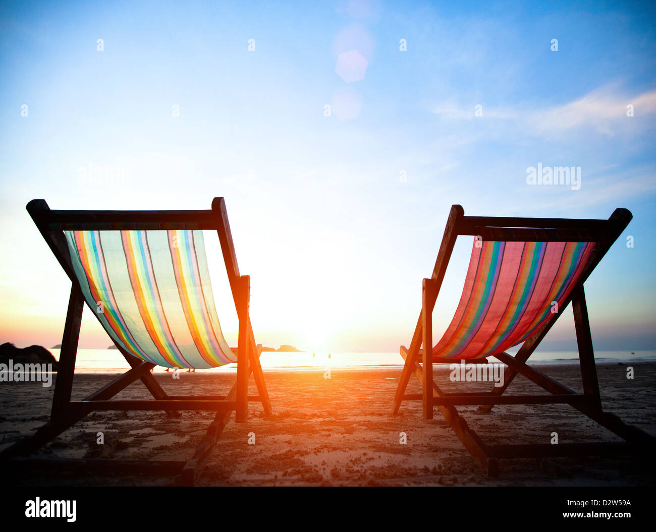 Vacation concept: Pair of beach loungers on the deserted coast sea at sunrise. Stock Photo
