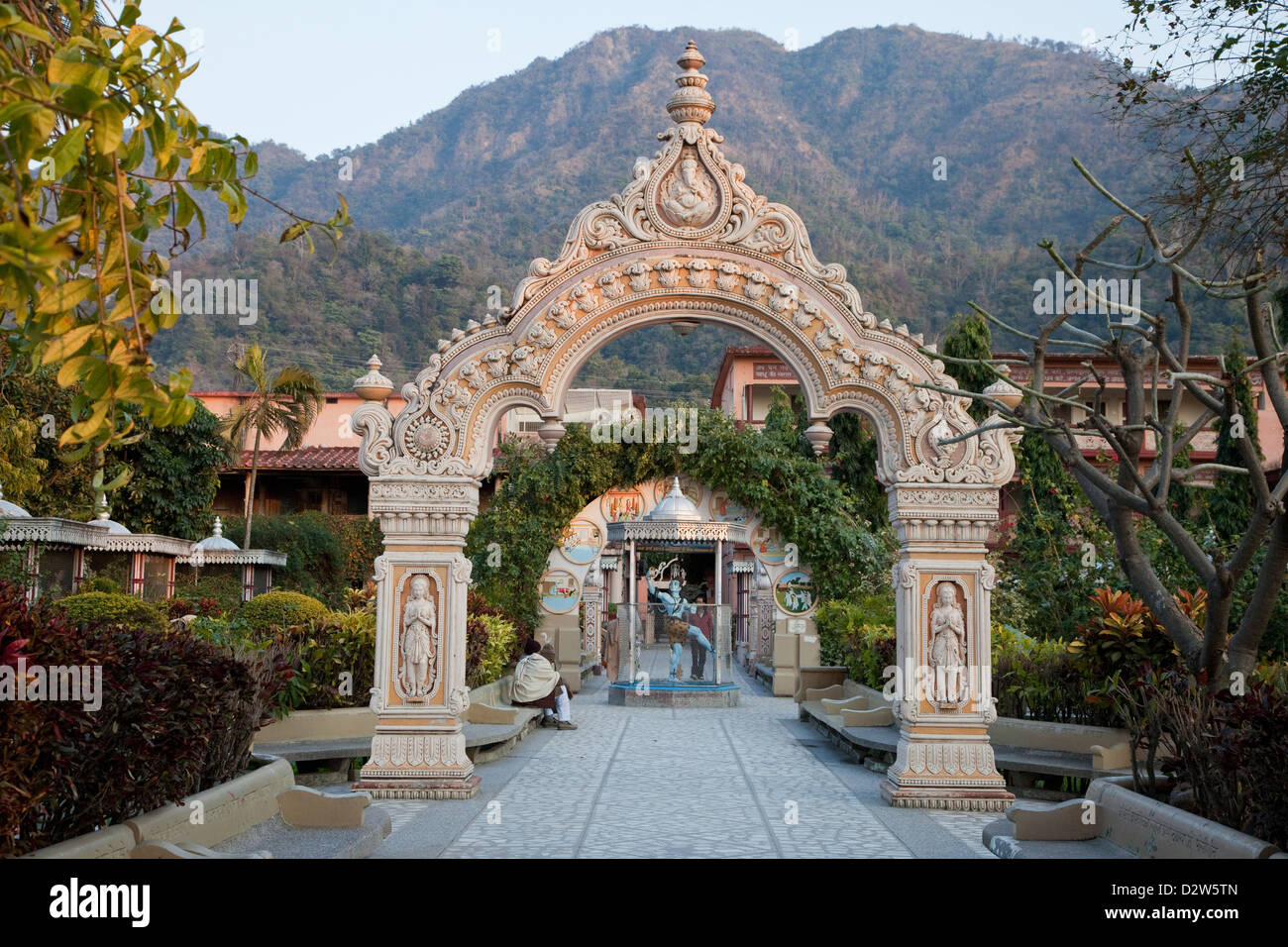 India, Rishikesh. Courtyard of the Parmarth Niketan Ashram. A blue-tinted statue of Shiva is under the second arch. Stock Photo