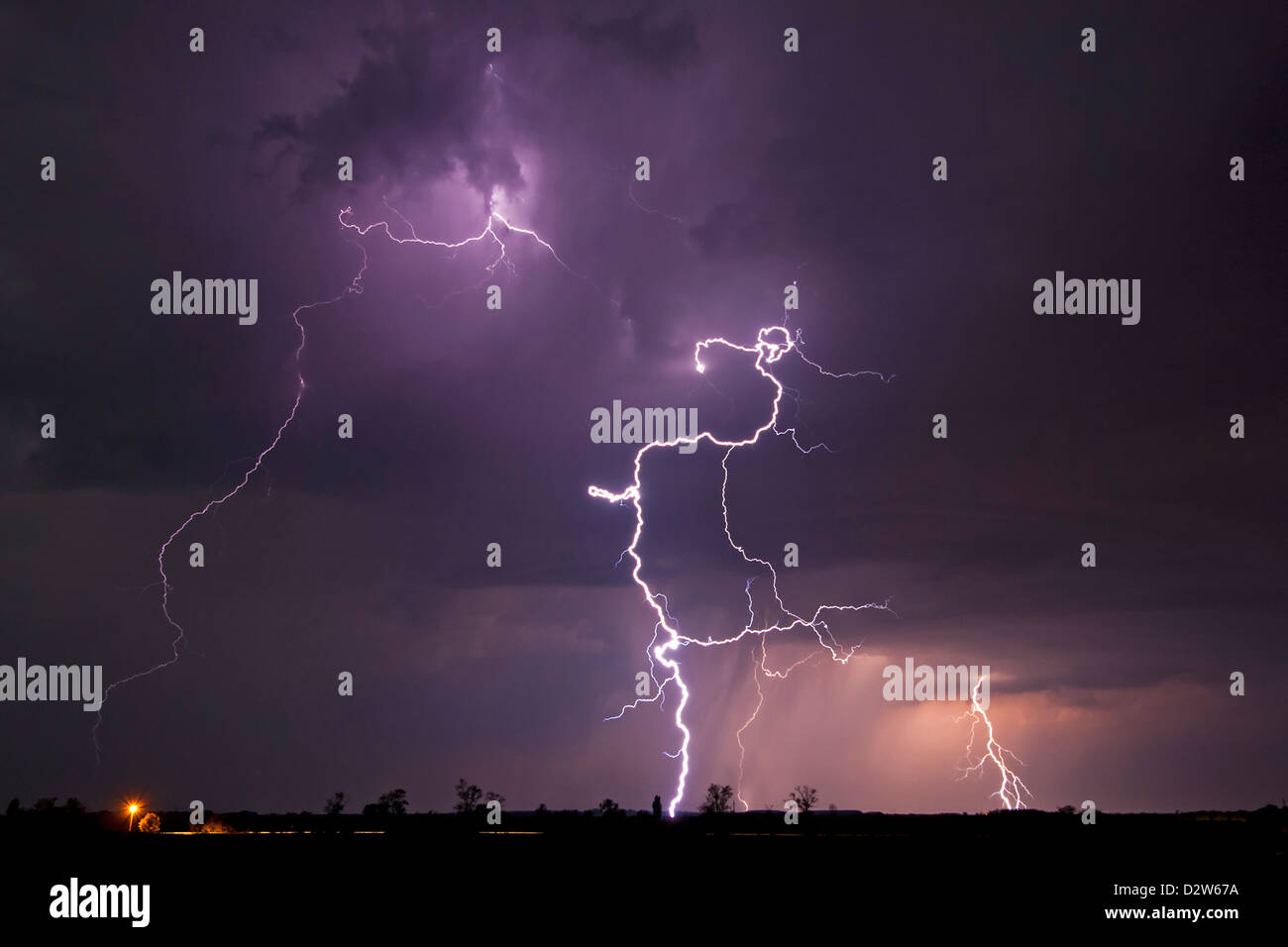 Lightning bolts lighting up the sky over a rural landscape Stock Photo