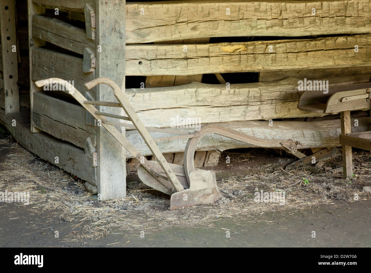 Plow standing in a barn against rough hand cut wood of a pen Stock Photo