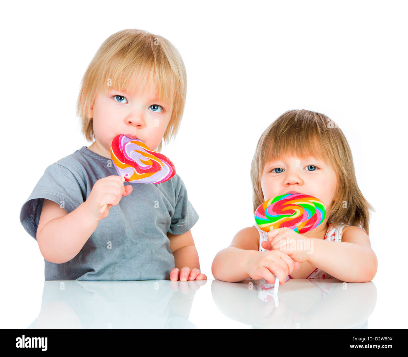 Babies eating a sticky lollipop on white background Stock Photo