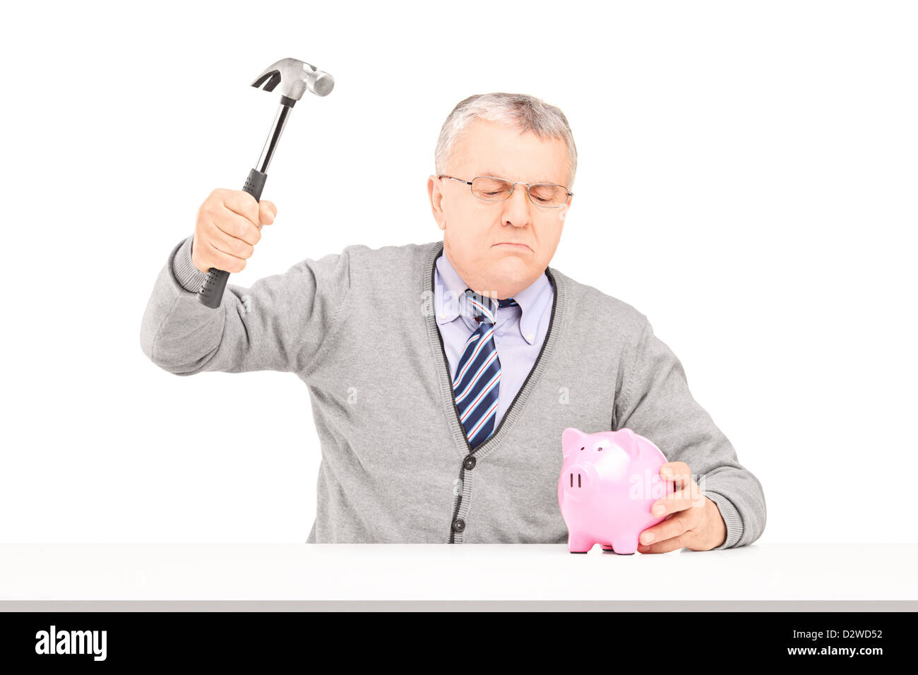 Angry mature man trying to break a piggy bank with a hammer isolated on ...