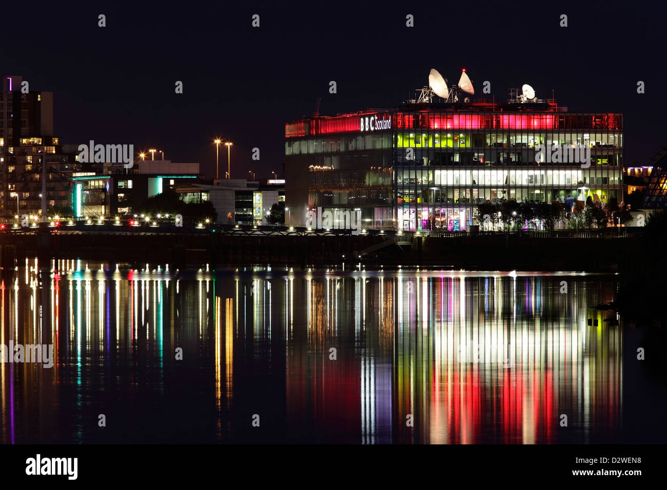 Looking East towards the illuminated BBC Scotland Headquarters on Pacific Quay reflected in the River Clyde at night, Glasgow, Scotland, UK Stock Photo