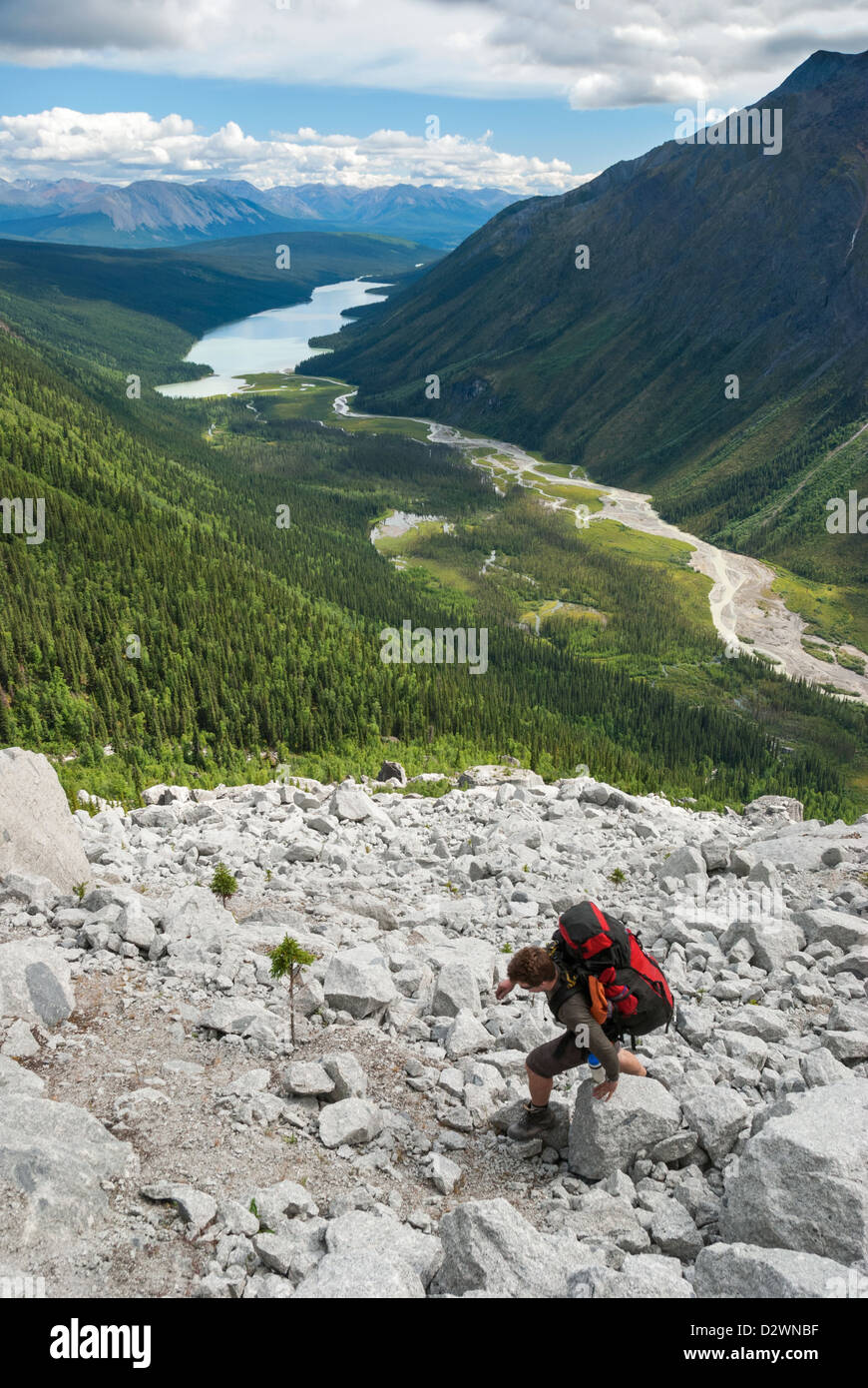 Backpacker ascending a steep talus slope on the route to the Cirque of the Unclimbables in Canada's Northwest Territories. Stock Photo