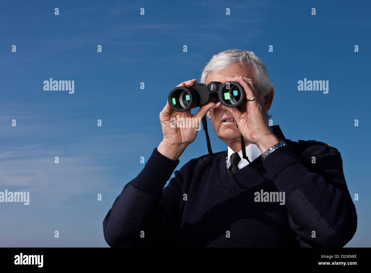 Coastguard looking through binoculars, Dorset, UK Stock Photo