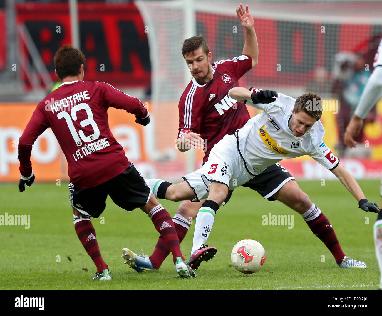 Gladbach's Patrick Herrmann (R) vies for the ball with Nuremberg's  Hiroshi Kiyotake (L) and Per Nilsson (M) during the German Bundesliga soccer match between 1. FC Nuremberg and Borussia Moenchengladbach at Stadium Nuremberg in Nuremberg, Germany, 03 February 2013. Photo: DANIEL KARMANN (ATTENTION: EMBARGO CONDITIONS! The DFL permits the further utilisation of up to 15 pictures only (no sequential pictures or video-similar series of pictures allowed) via the internet and online media during the match (including halftime), taken from inside the stadium and/or prior to the start of the match. T Stock Photo