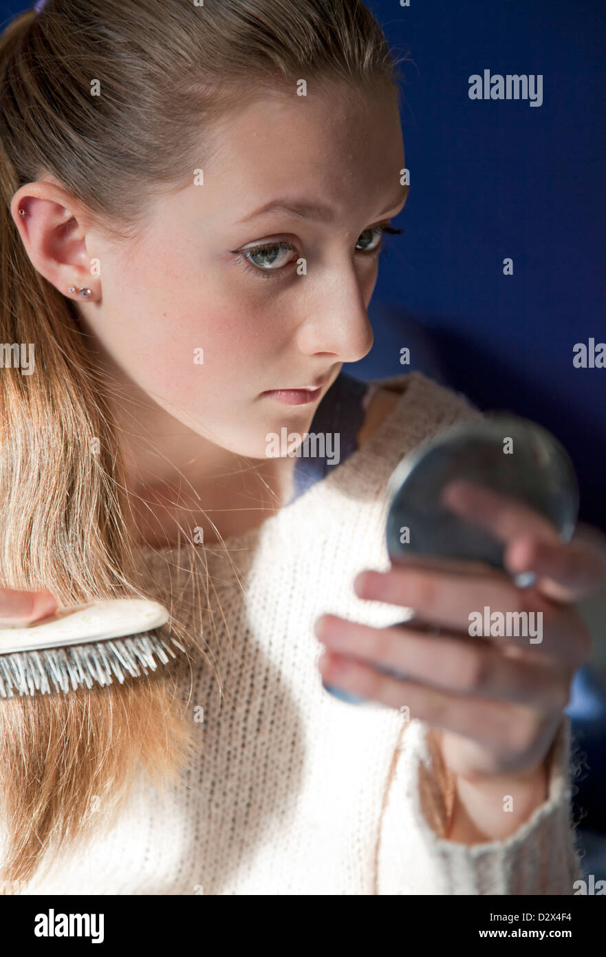 Young teenage girl brushes her hair in a small hand mirror Stock Photo ...