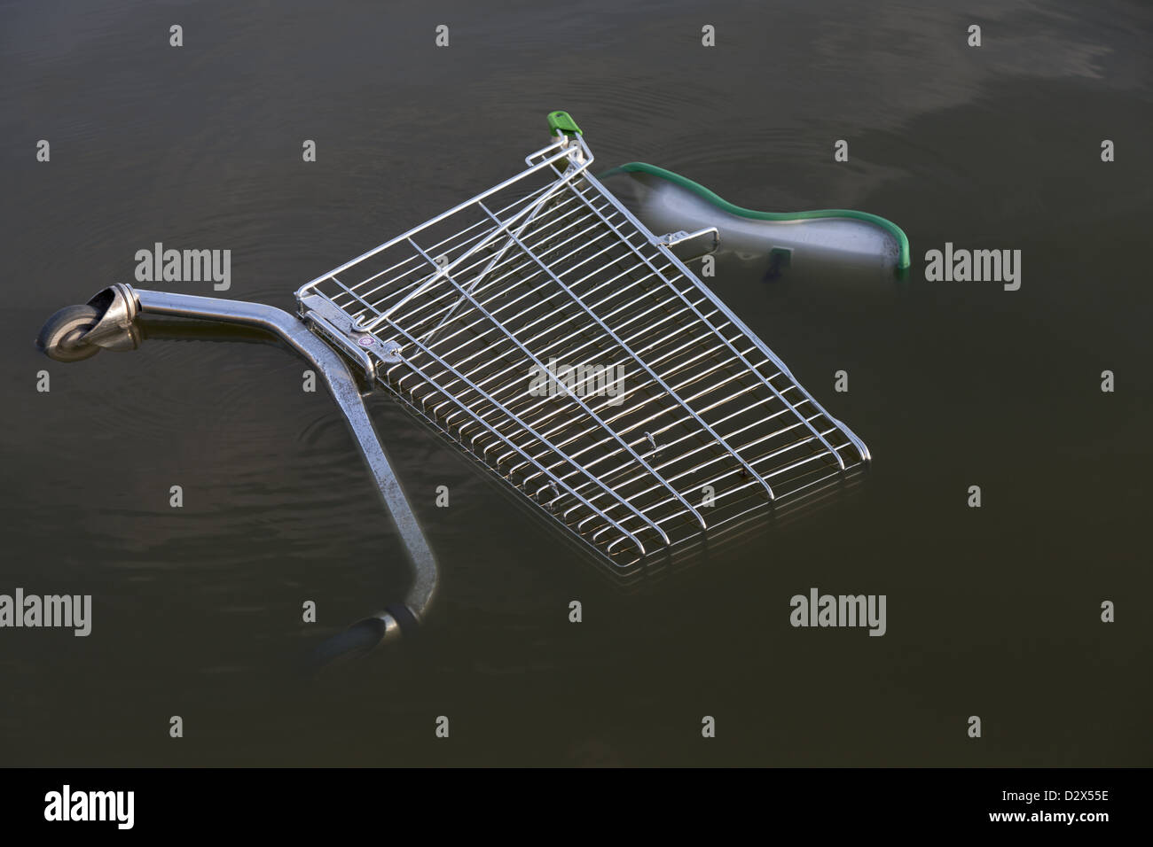 A shopping trolley laying sideways abandoned in water Stock Photo